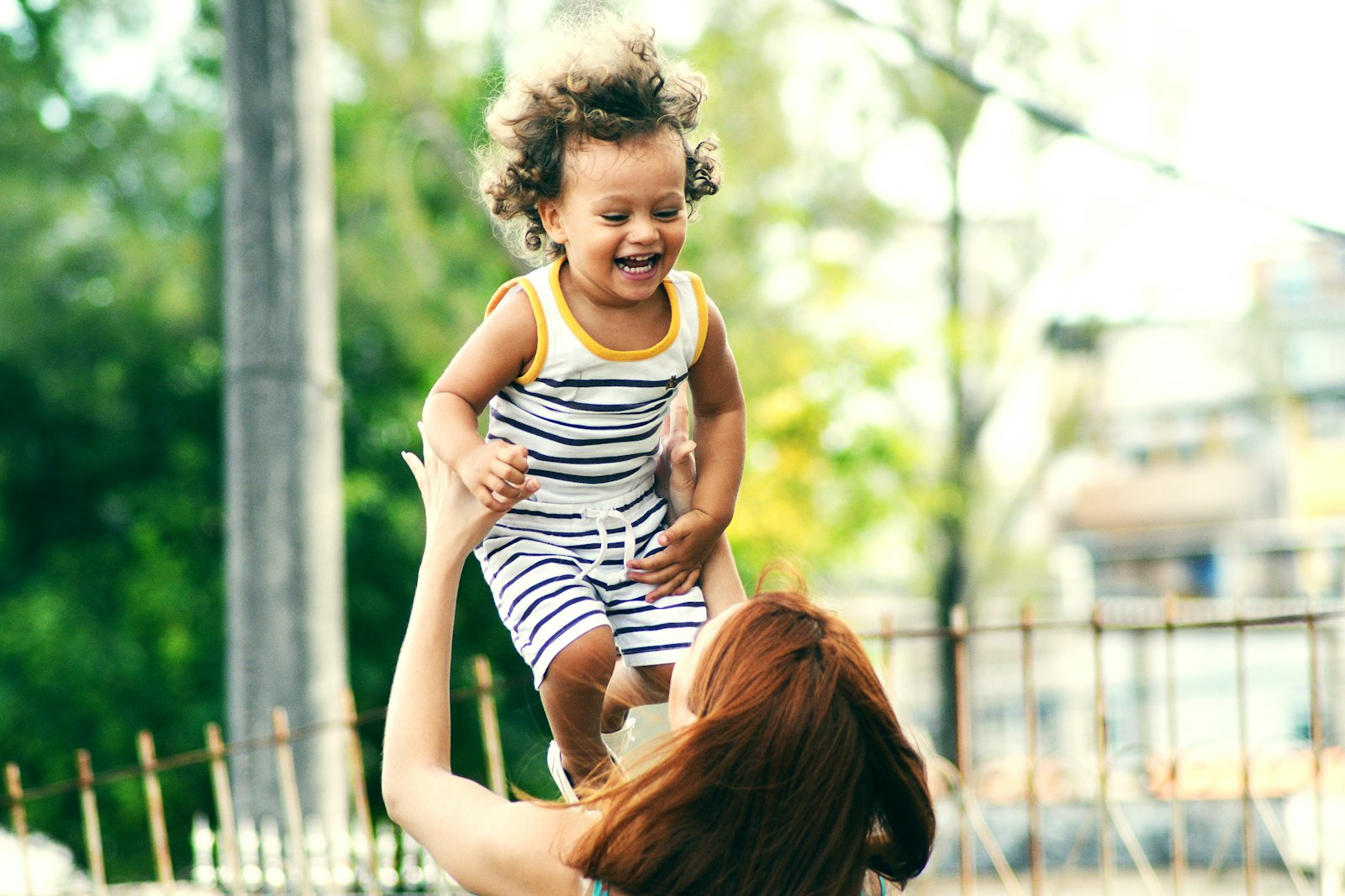 A parent lifting a laughing child in the warm evening light